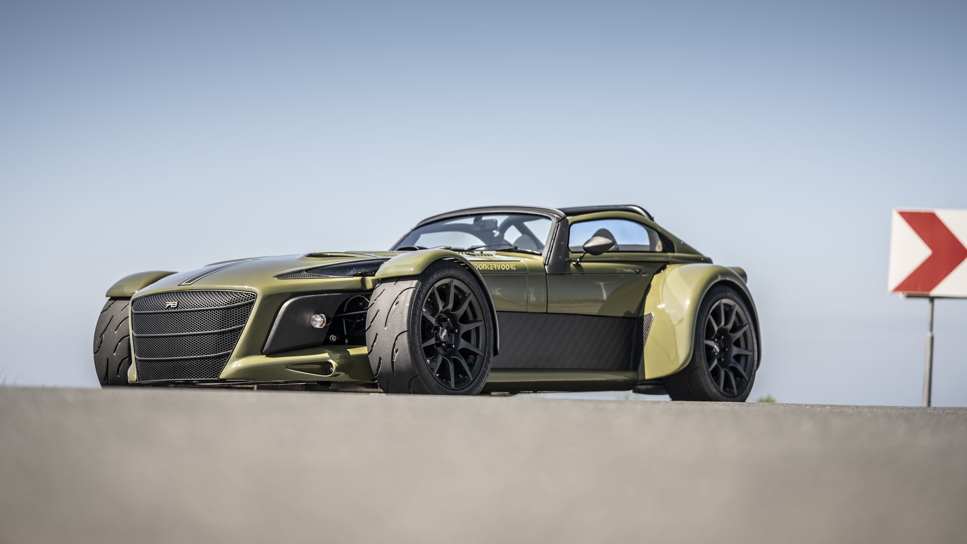 View of a green Donkervoort D8 GTO-JD70 on tarmac agains a clear blue sky